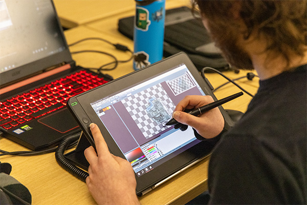 Image of student drawing on a digital pad during last year's Global Game Jam site at DSU.